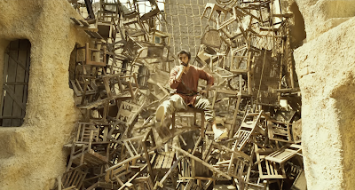 Ranbir Kapoor sits on top of a perilous stack of wooden chairs in an alley