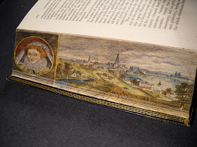 The bent fore edge of a book, which reveals a landscape and portrait of Queen Elizabeth.