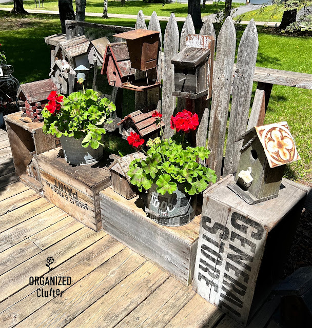 Photo of a rustic outdoor birdhouse display with plants.
