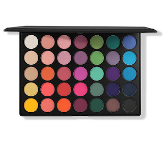 A black rectangular thick plastic case containing circular pans of different coloured eyeshadows including blue, pink, orange and green on a bright background