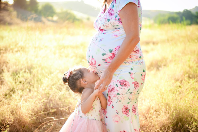 maternity shoot of daughter kissing moms belly