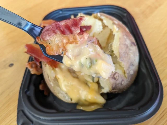 Side view of Wendy's Bacon Queso Baked Potato with a forkful.