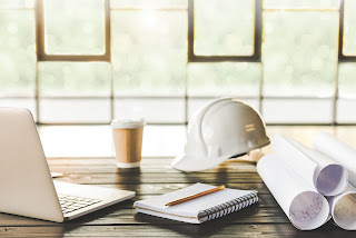 hardhat, laptop, blueprint and notebook on a table