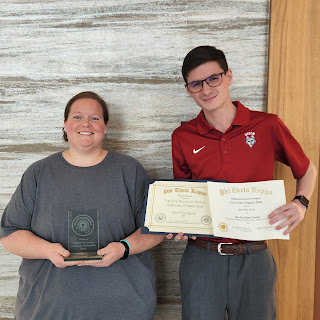 PTK members, April Brown, to the left, and Cody Porter, to the right, show off the chapter awards earned at the regional meeting.