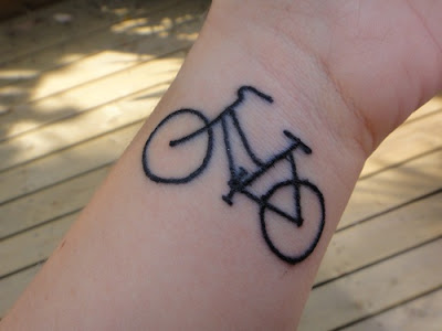 on dirt bike wheel tattoo. Black ink bicycle tattoo on wrist