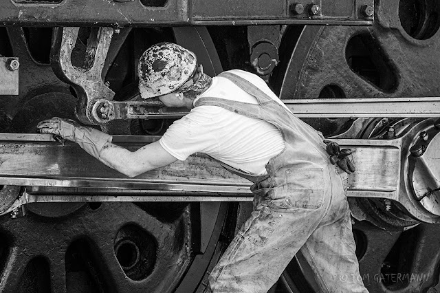 A member of UP 844's crea is cleaning and lubricating the locomotive's running gear.