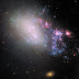 Галактика засиява от раждането на млади звезди, провокирано от близка среща с друга галактика (видео)