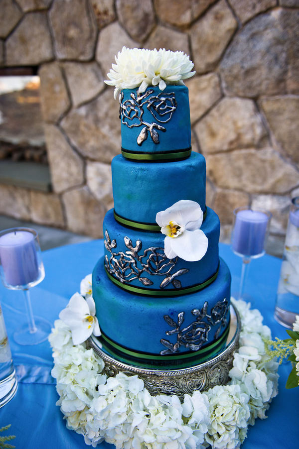 A beautiful rich blue wedding cake set over four tiers adorned with fresh