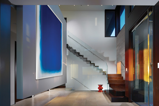 Picture of large high ceiling hallway with modern staircase and abstract painting on the wall