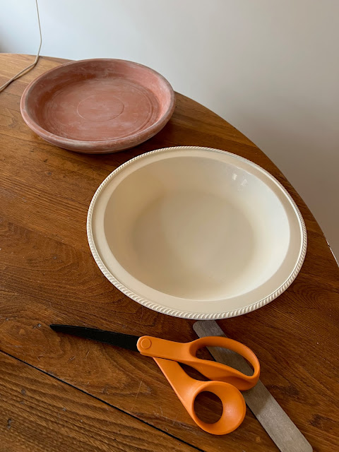 Photo of a terracotta saucer and a metal painted bowl.