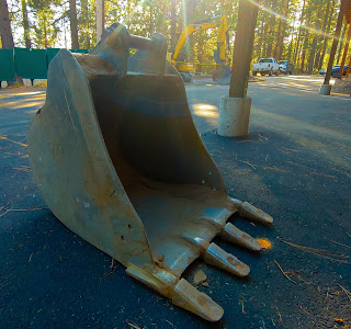 A digging claw of an excavator set on the concrete of a construction site