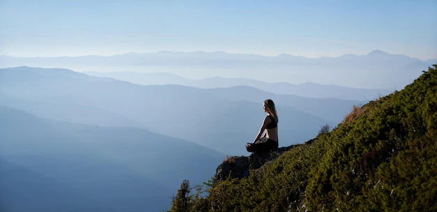 young woman meditating in mountains