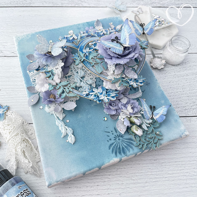 Rhapsody in Blues mixed media canvas created with: Reneabouquets ice fairy butterflies, sweet pea baby blue butterfly, fairy dust butterfly kisses, drop lace, diamond glitter glass, elegant accents chipboard, blue lilac heart frames beautiful board; Prima Marketing the plant department flowers; Tim Holtz distress sprays