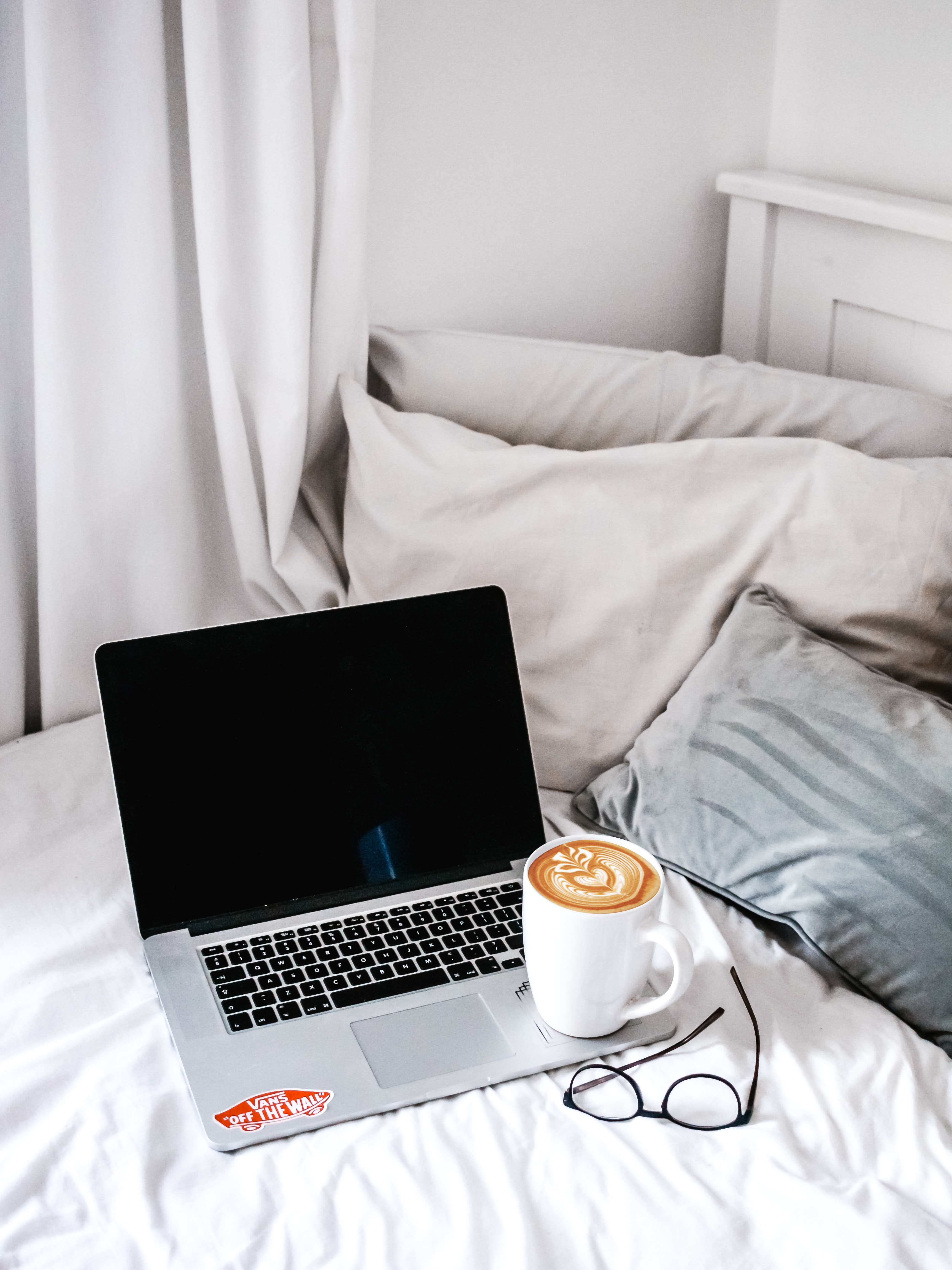 computador mac e caneca de café na cama do quarto