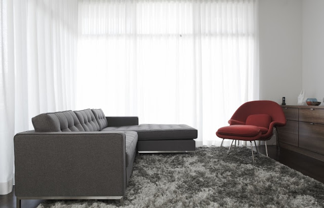 Picture of dark grey sofa and red chair in the grey carpet in the minimalist living room