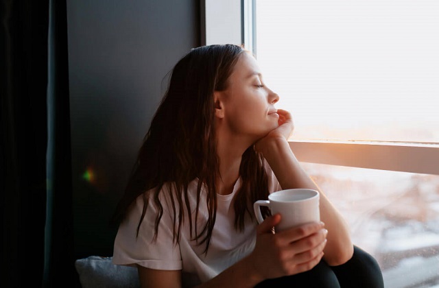 Woman sitting comfortably by the window with coffee