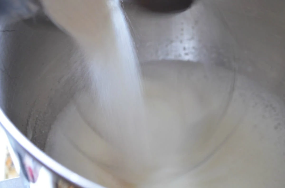 Sugar slowly poured into egg whites while mixer runs.