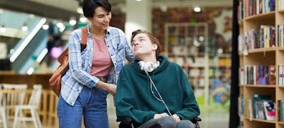 Young wheelchair-bound man with female aide photo