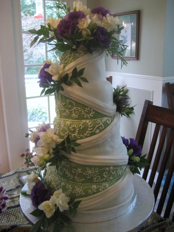 Green and white fondant four tier wedding cake with purple and white roses