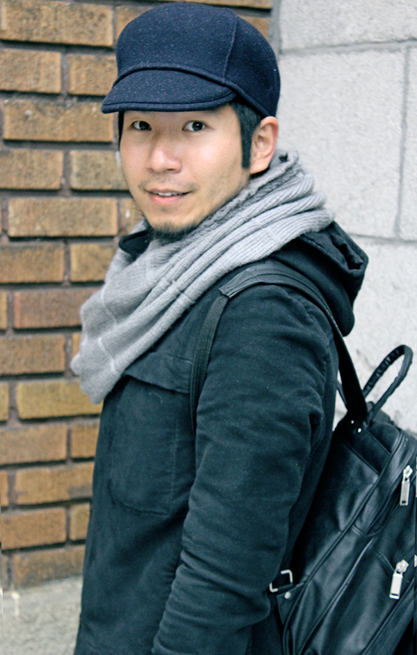 Montrealer Man in Japanese Student style, wearing black long cotton hoodie coat designed by Stephan Schneider and dark navy blue wool cap hat