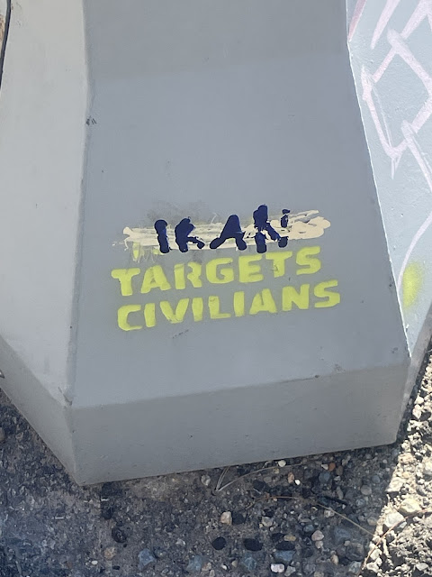 Yellow graffiti: "Israel Targets Civilians" but "Israel" is blotted out and replaced with "Iran"