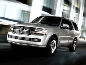 Silver 2011 Lincoln Navigator front 3/4 view driving on city street at night