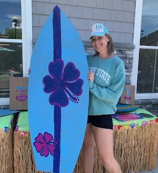 Woman standing outside holding blue surfboard at The Heights Amesbury