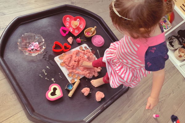 pressing feet into the dough on the Valentine's Day sensory rose playdough tuff tray