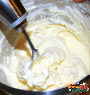 A bowl of cream cheese mixture being prepared with a hand mixer.
