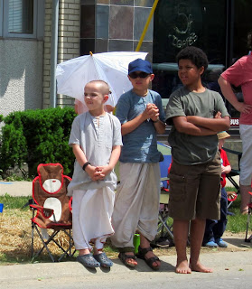 harikrishna kids watching parade, shaved head, ponytail sandals