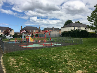 A playground with houses in the distance.