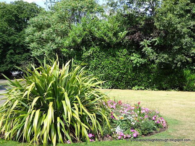 Trees in leaf, and flowers blooming in park setting