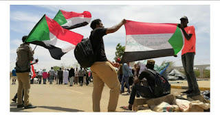 Young Sudanese carry a national flag as they rally in the capital Khartoum on April 14, 2019. ASHRAF SHAZLY / AFP  