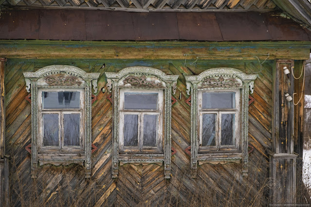 Три окна старого дома в резных наличниках