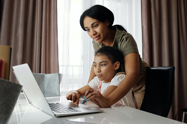 a black teacher teaching a black student how to safely use the internet