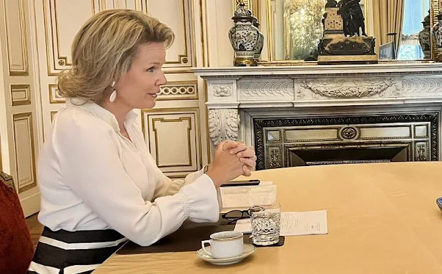 Queen Mathilde wore a striped midi skirt by Natan. White earrings. Olena Zelenska wore a green silk shirt