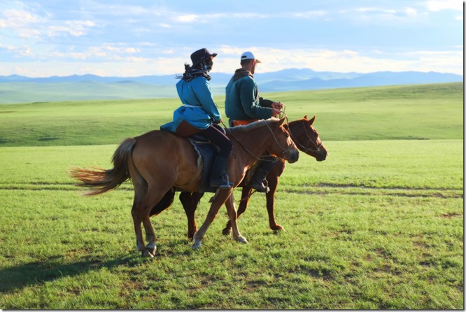 モンゴルの草原で馬に乗る男女