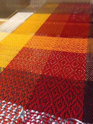 A bright color gamp, with warp running in panels from left to right of white, yellow, orange, red, and purple, and weft blocks in a variety of colors. Every new weft color also shows a new set of twill patterns.