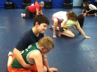 Sports camp students wrestling on mats.