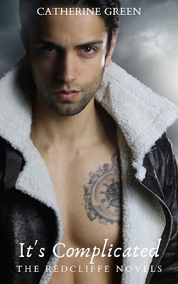 Image of a sexy man showing a tattoo on his chest staring at the viewer with a sultry gaze. Vampire and werewolf fantasy books for adults. Book cover for "It's Complicated (The Redcliffe Novels)" by LGBT fantasy book writer Catherine Green.