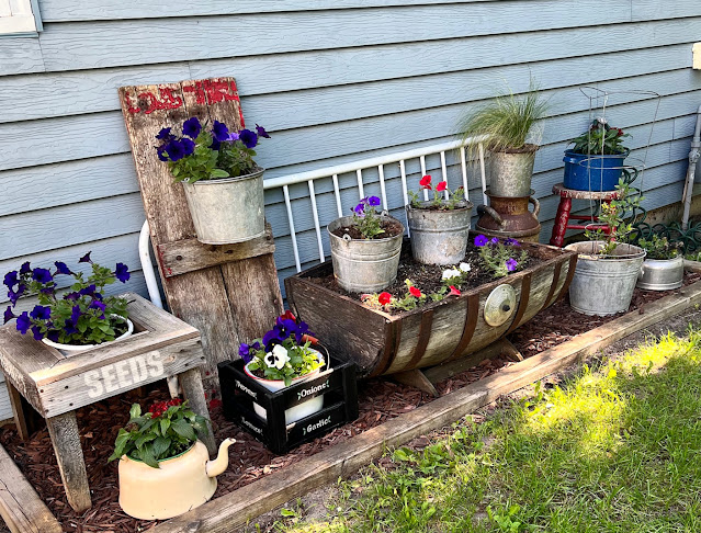 Photo of a junk garden containers along the back wall of the house.