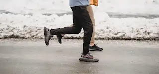 Unidentified athletes are pictured jogging on a snowy path.  physical strength