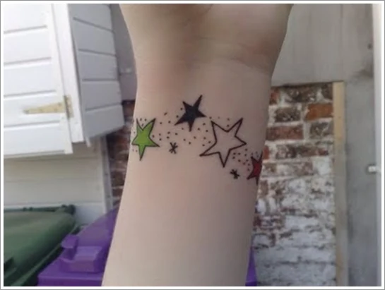 tatuaje en la muñeca de una mujer, es un brazalete de estrellas de colores