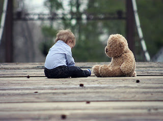 niño sentado con su oso enfrente