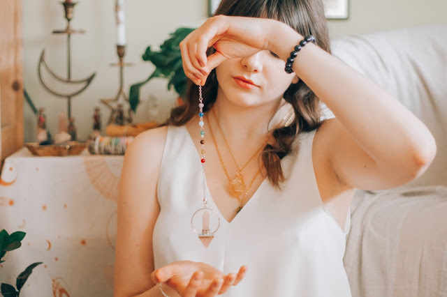 A brunette woman holding up her necklace.