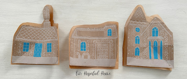 three paper gingerbread houses with blue windows