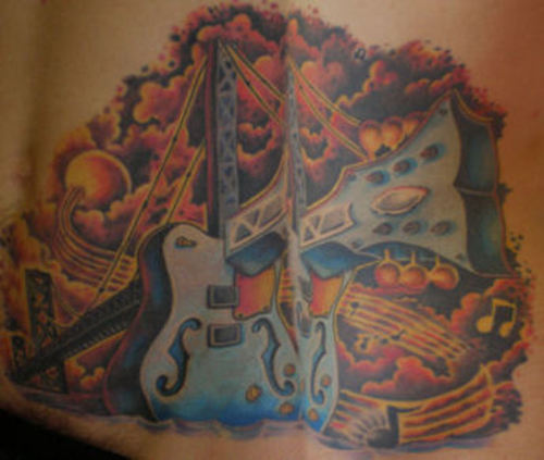 Guitar Tattoo Design with skull and fire on guys upper arm