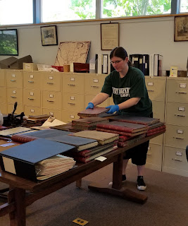 Photo of Marietta arranging large books on a table in the SCHS library.