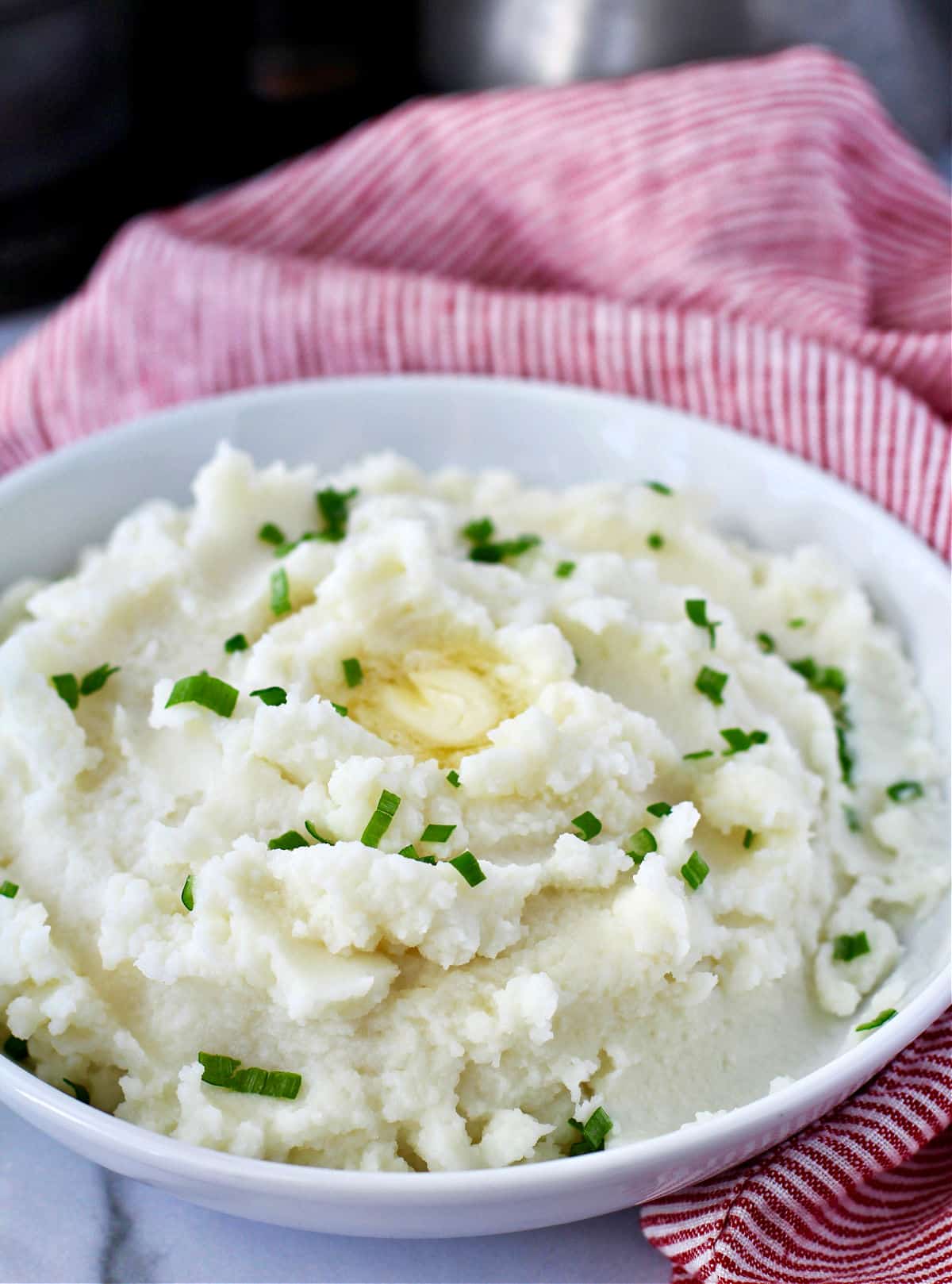 Creamy Garlic Mashed Potatoes with butter and chives on top.