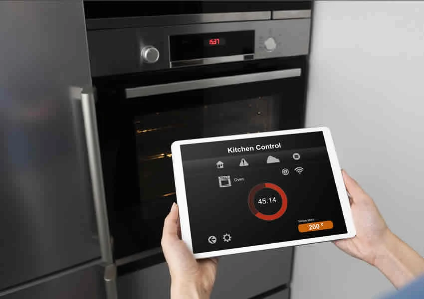 Imagem mostra uma pessoa controlando um forno via dispositivo móvel.